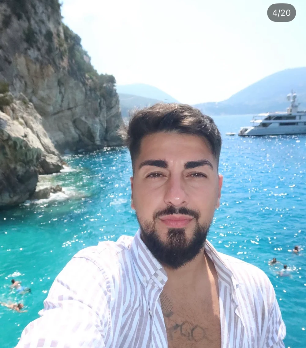 Patrick taking a selfie beside a sunlit sea and cliffs
